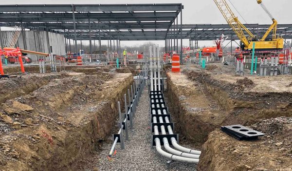 PMT Site data center project - utility trench with conduit bundles in foreground, data hall steel structure and tower crane in background