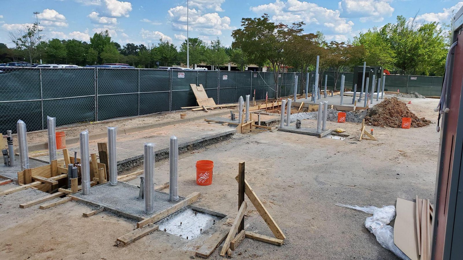 PMT Site crews installing conduit risers and concrete pads for EV charging stations at a commercial deployment site